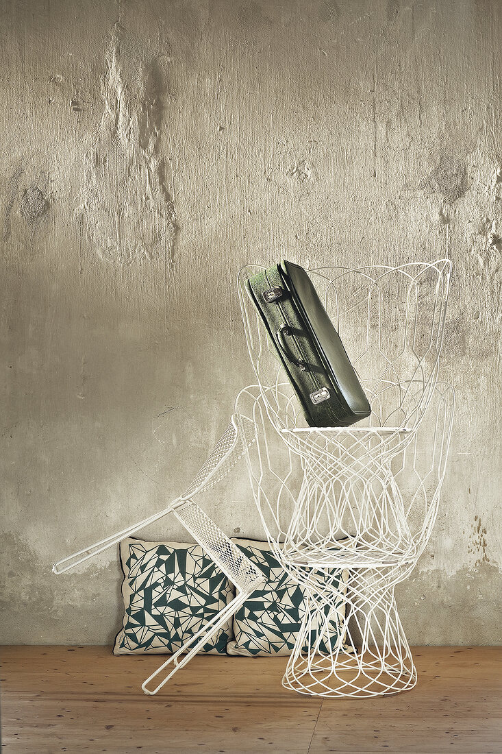 White metal chairs and suitcase stacked in room