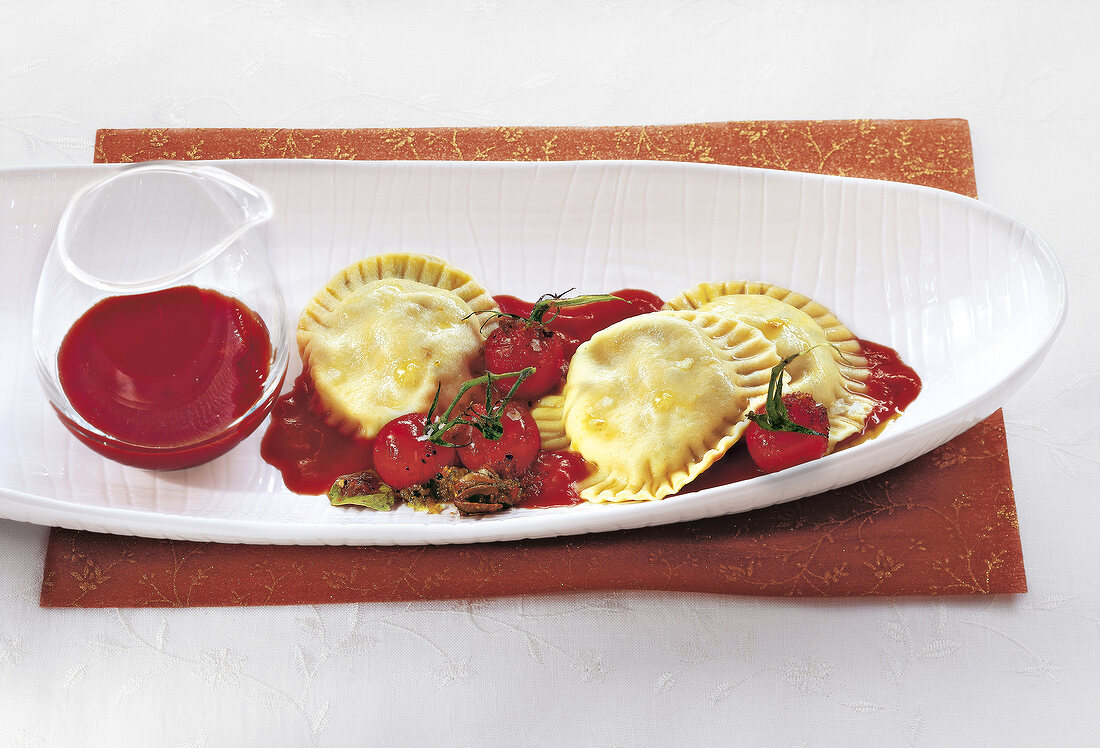 Herb ravioli with tomato sauce on oval plate