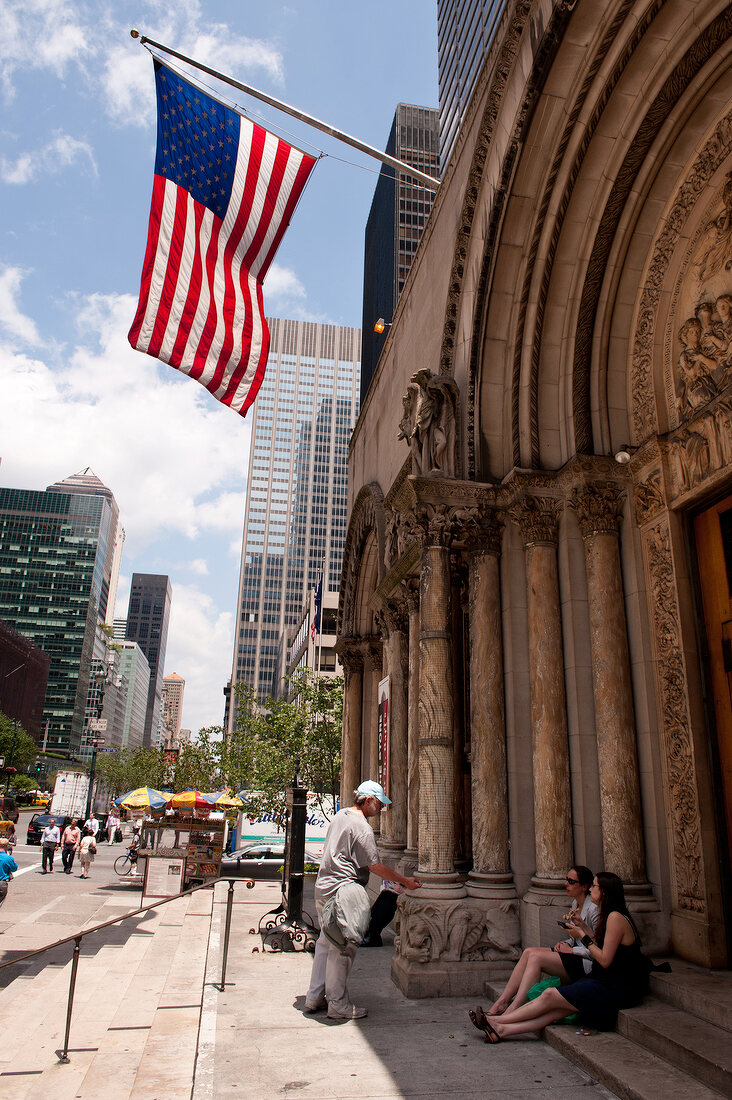 Tourists sitting outside Saint Bartholomew's Episcopal Church in Manhattan, New York, USA