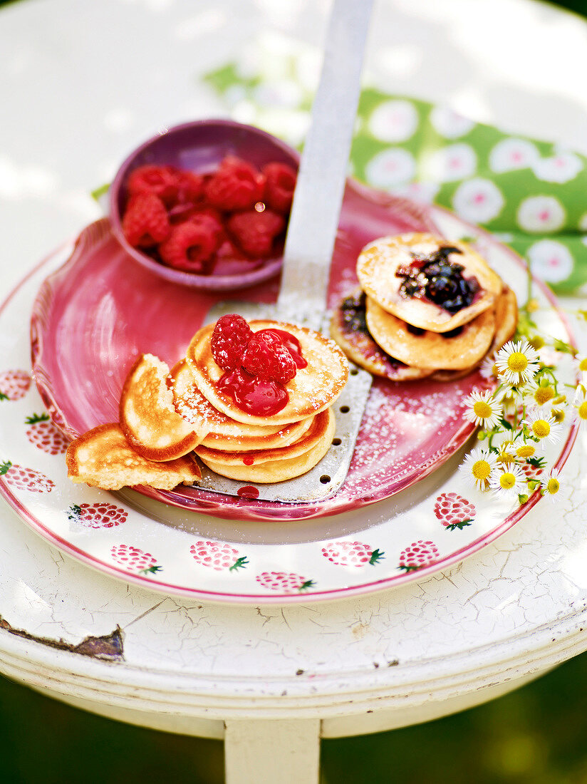 Two stacks of pancakes with different berries on plate, garden kitchen