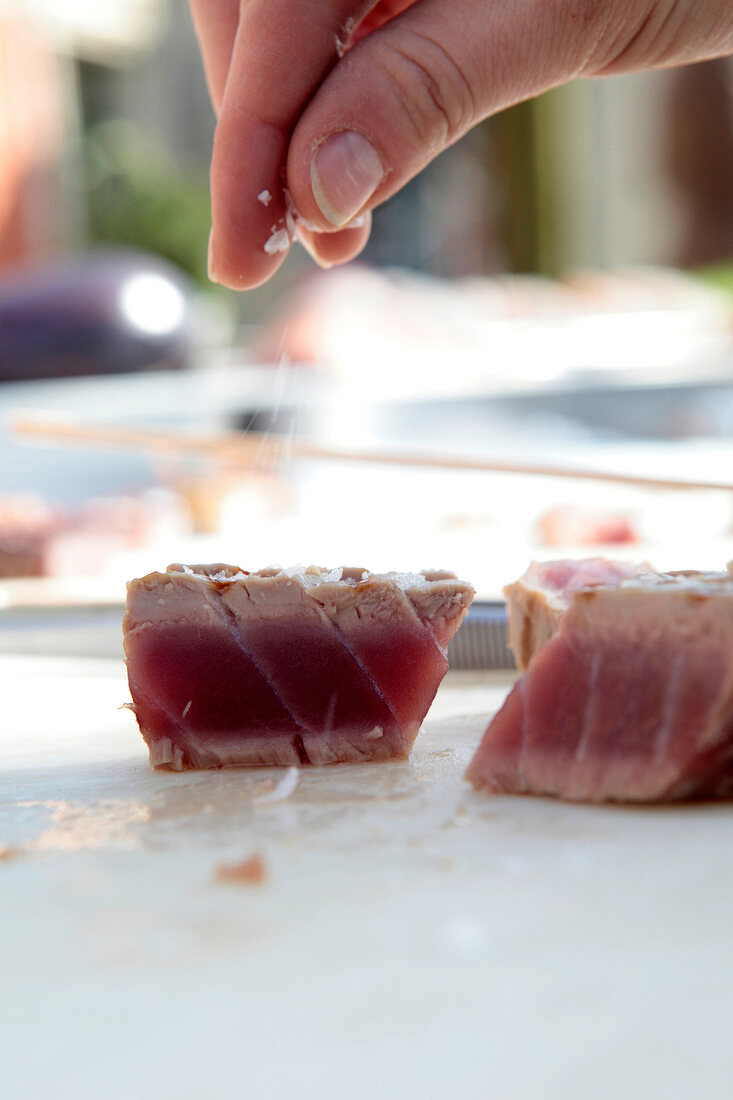 Meersalz wird auf einen medium rare gegrillten Thunfisch gestreut