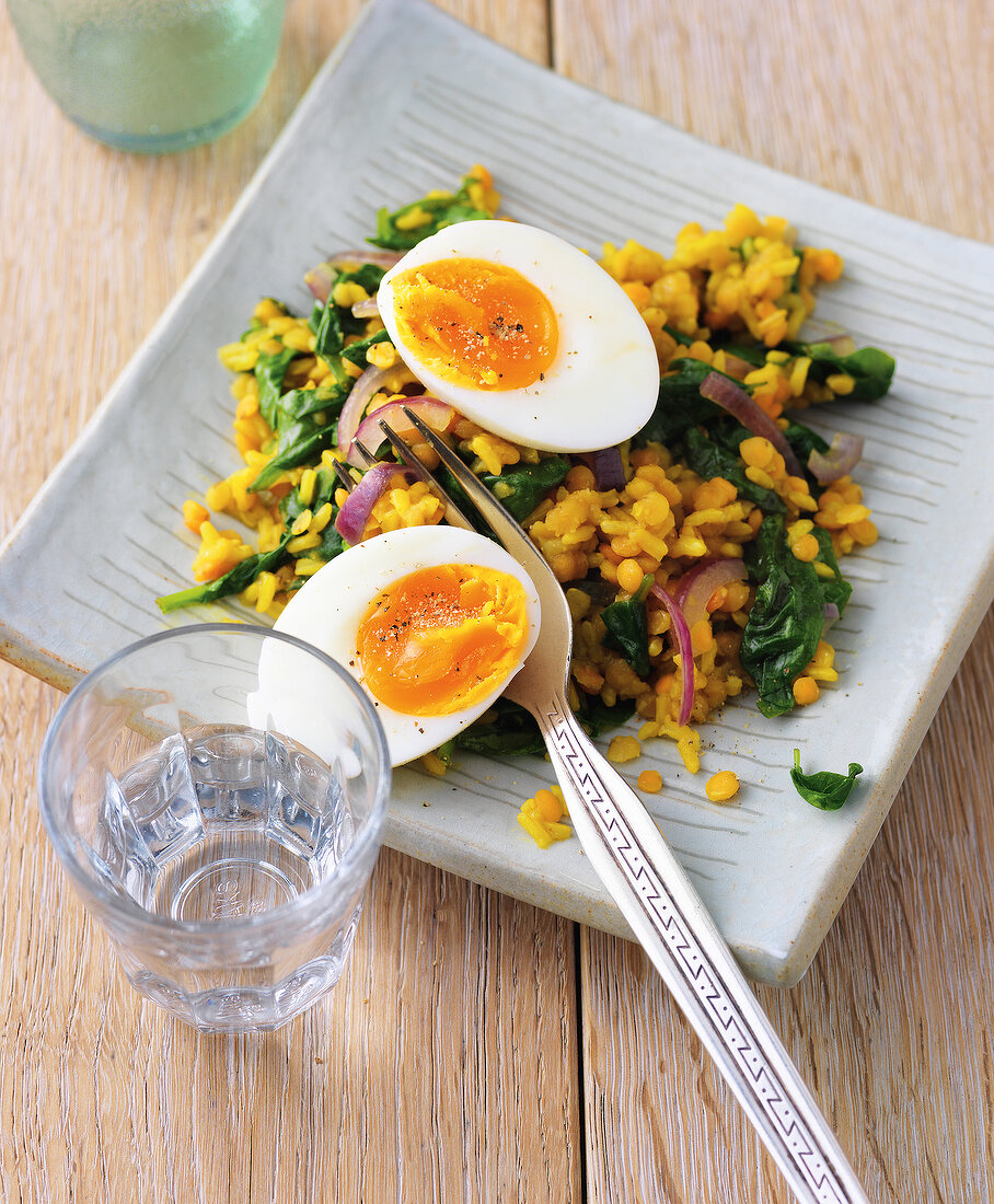 Yellow lentil rice with spinach and egg in serving dish