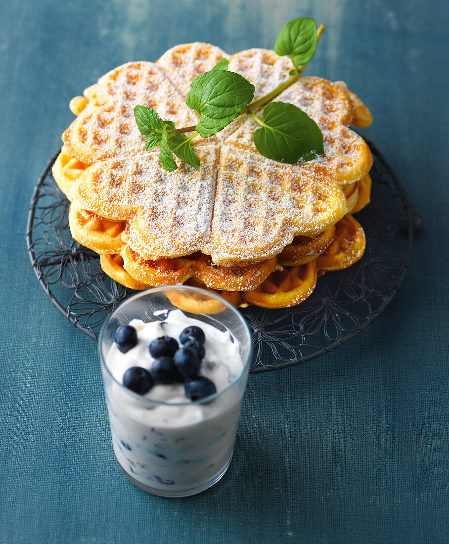 Vanilla waffles on wire coaster with blueberry curd in glass