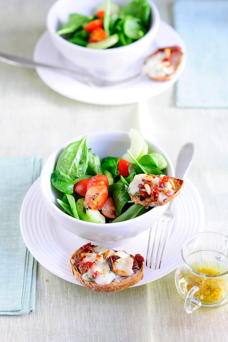 Spinach salad with goat cheese crostini in bowl