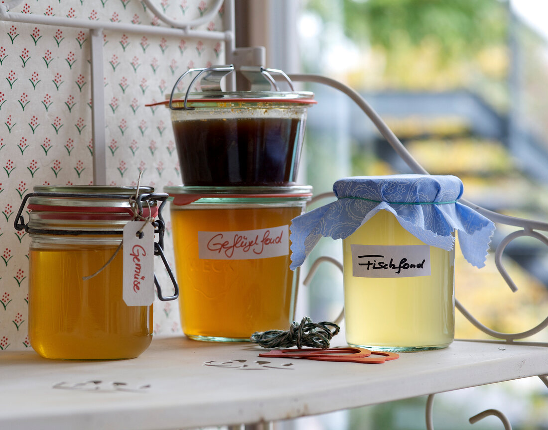 Four different homemade fonds in jars on shelf