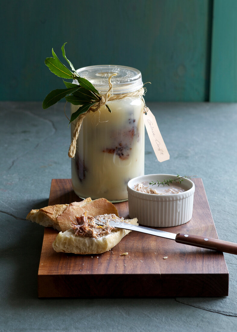 Homemade goose confit in jar and duck rillettes with bread on chopping board