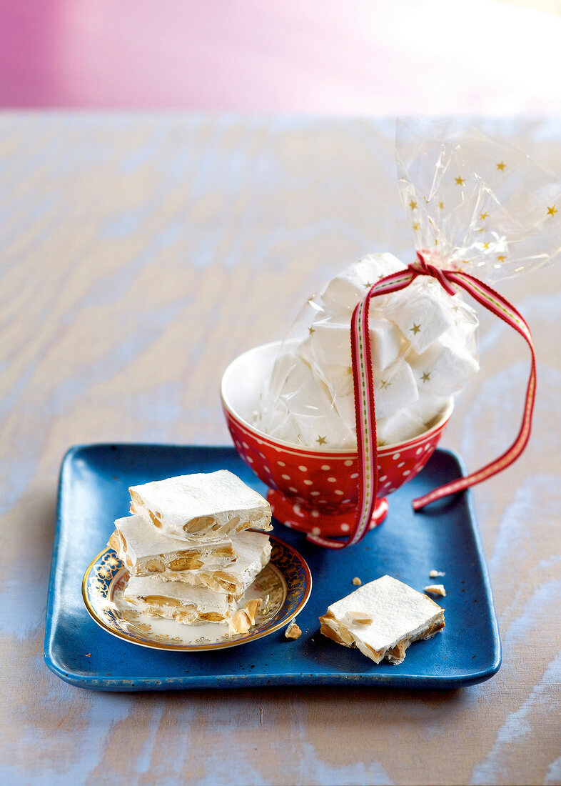 Homemade white nougat and bowl with marshmallow on blue tray