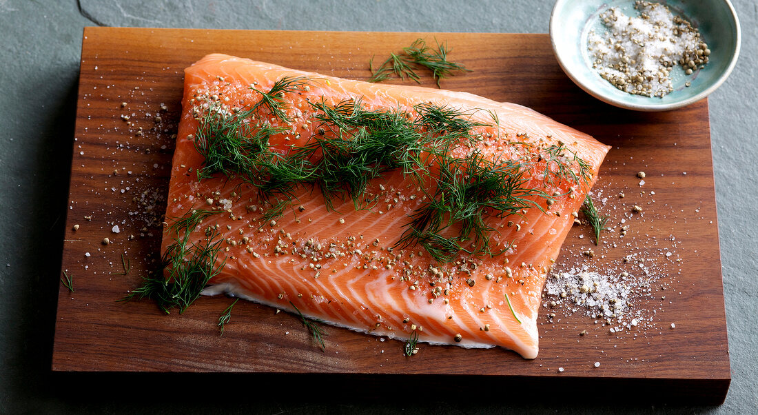 Sprinkled salmon fillets with salt and dill on wooden board