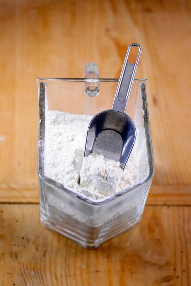 Flour in glass container on wooden surface