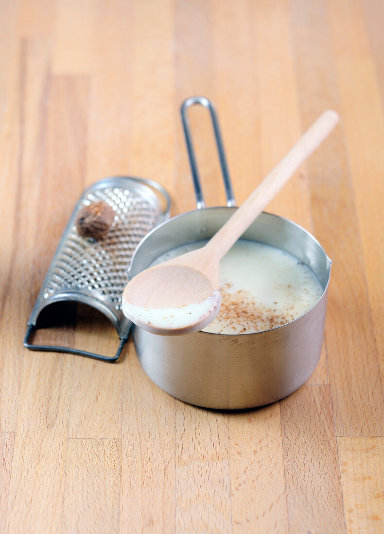 Bechamel sauce in sauce pan on wooden surface