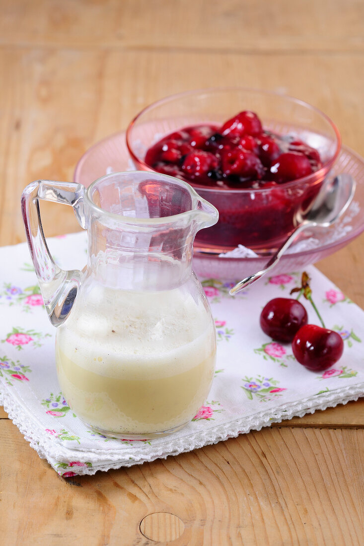 Red fruit jelly in bowl with vanilla sauce in jug