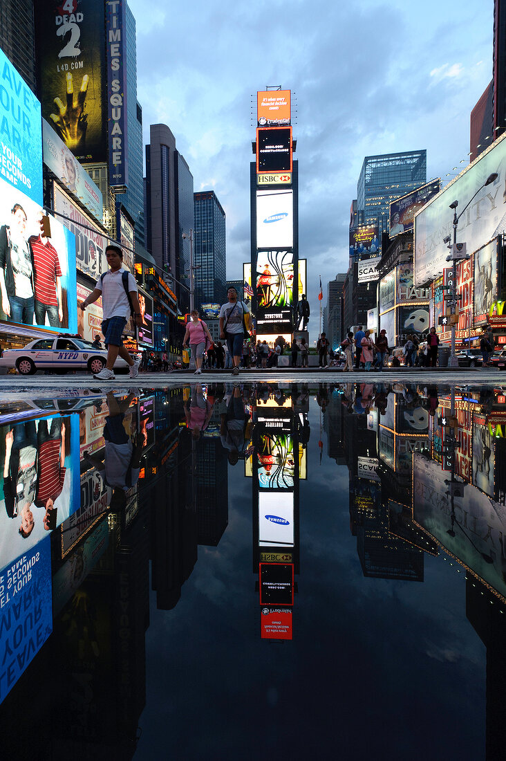 Reflection of illuminated advertisements on puddle at Times Square in New York, USA