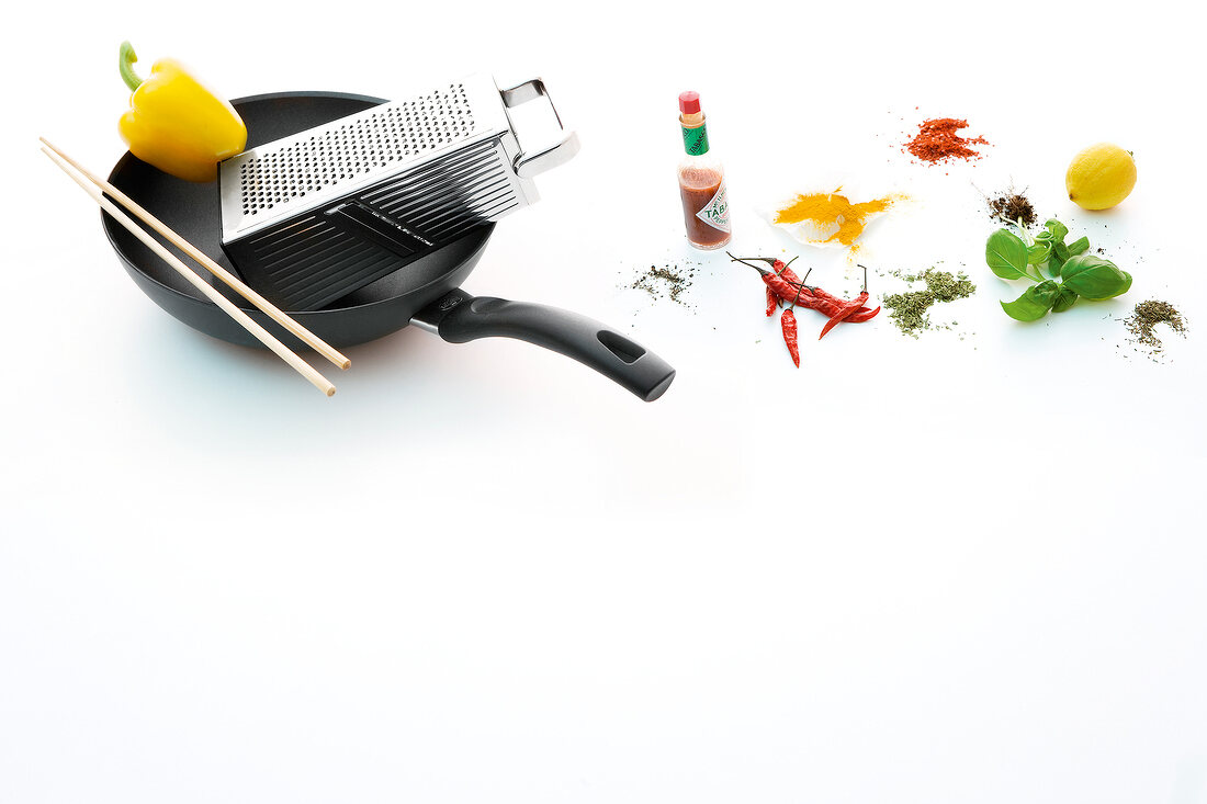 Wok, grater, chopsticks, tabasco, chilli and basil on white background