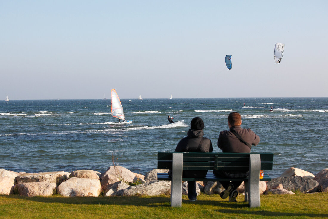 Couple watching lake surfing and parachutes at Baltic Coast, Schleswig-Holstein, Germany