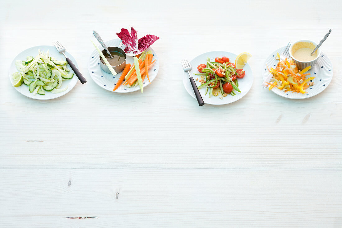 Four plates with raw food on white background