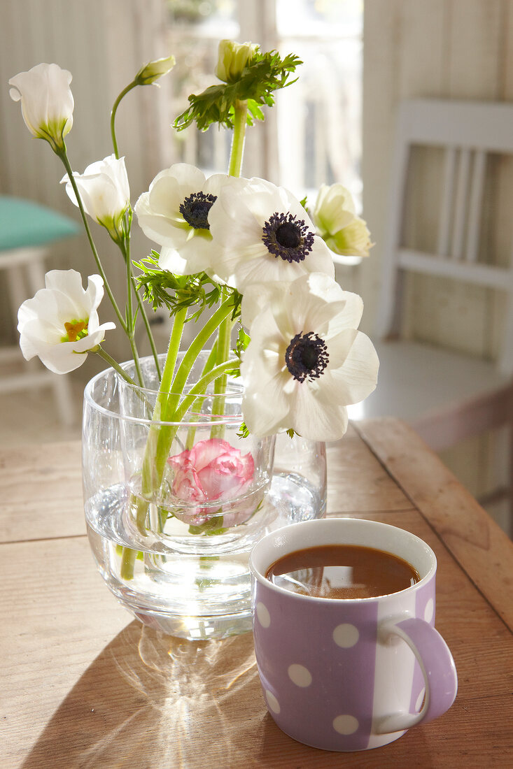 Close-up of cup with anemone and lisianthus in glass vase