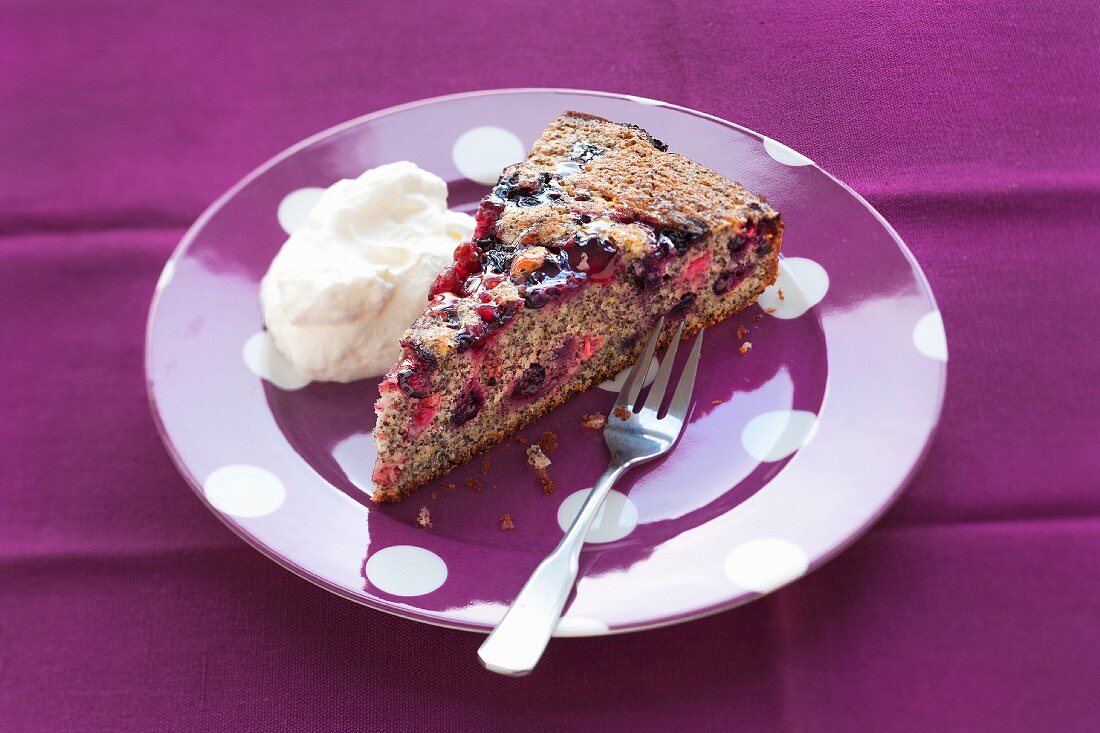 A slice of redcurrant cake with poppyseeds and cream