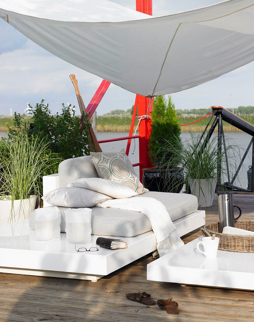 Sofa and coffee table below awning on waterside wooden deck