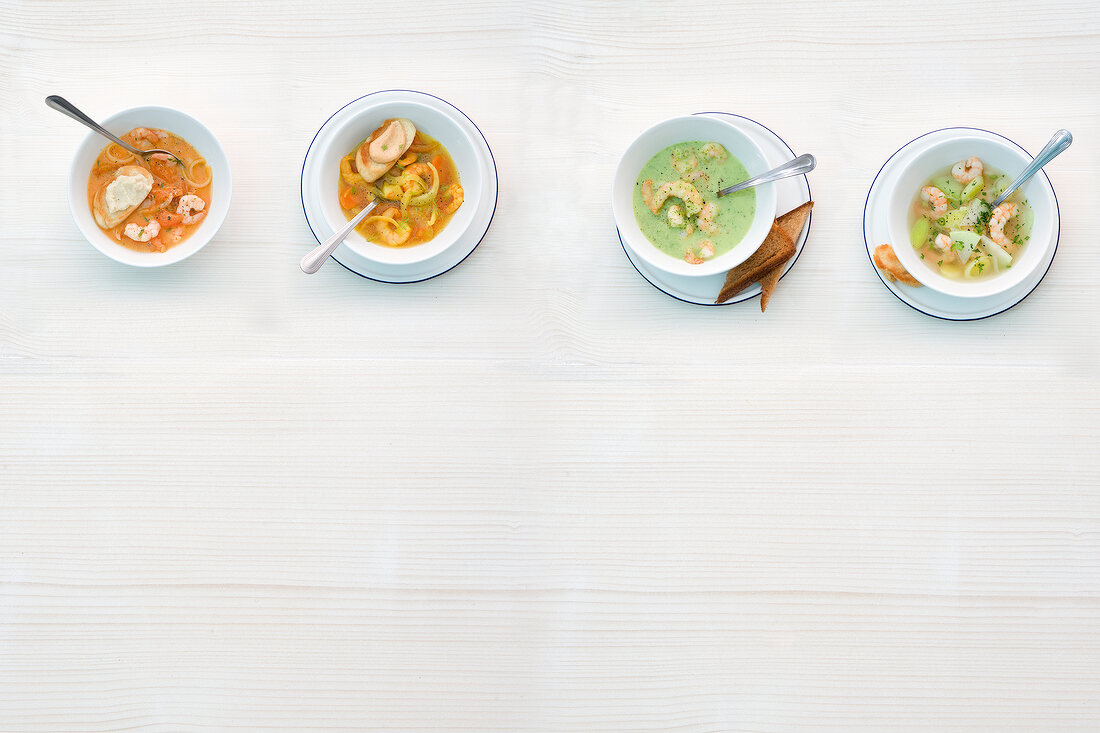 Four different type of soups with shrimp in bowls