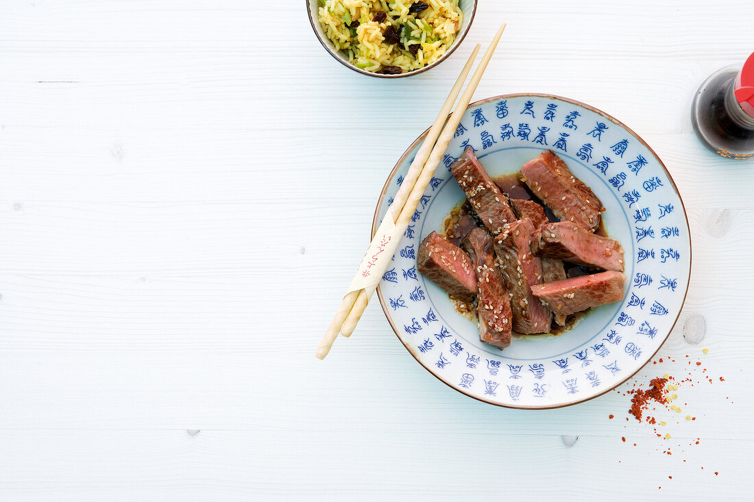 Asian steaks with sesame sauce and chopsticks on plate