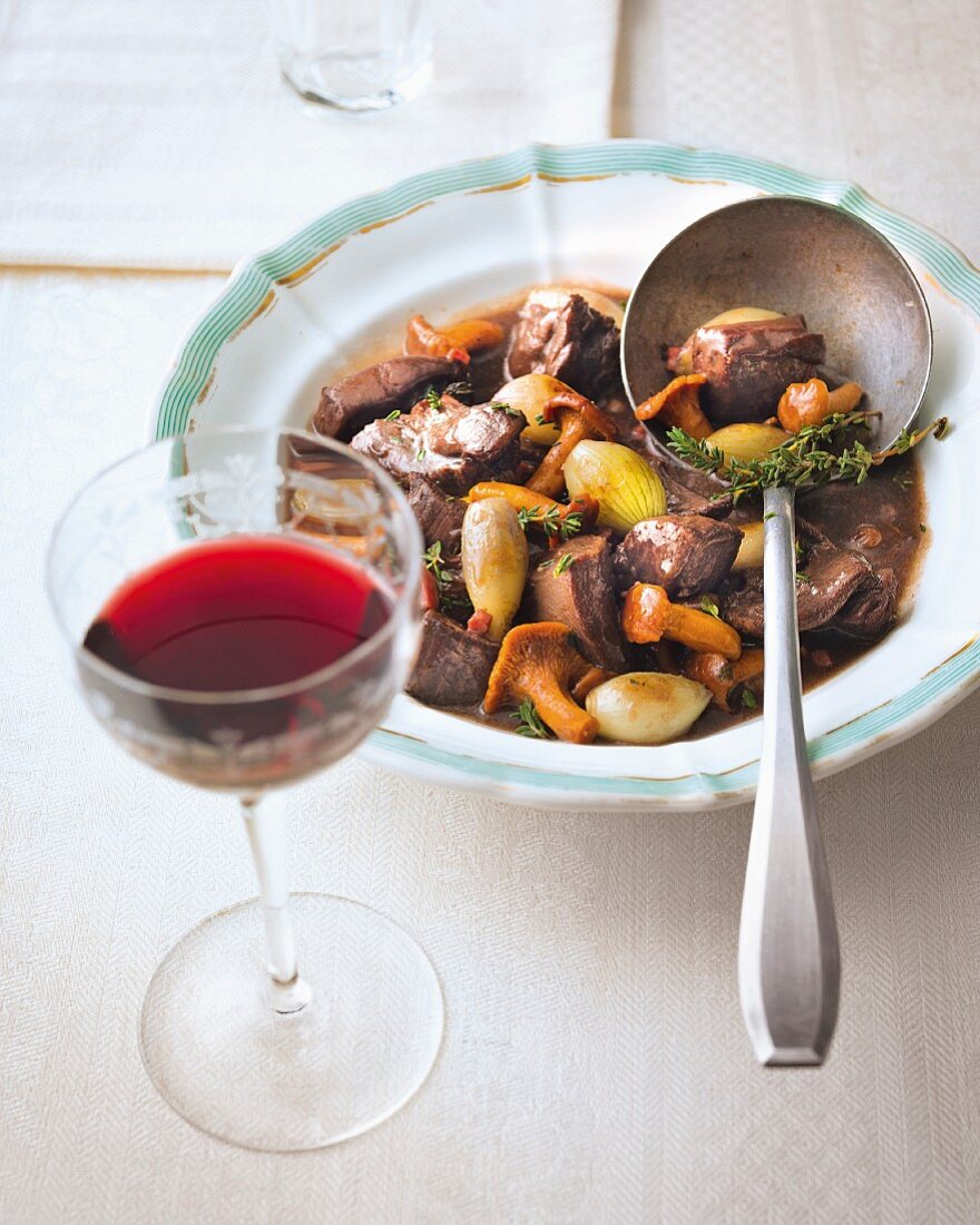 Game goulash with chanterelle mushrooms and a glass of red wine