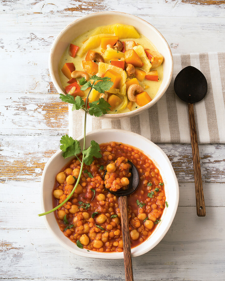 Chickpeas dal and pumpkin and pineapple curry in bowls, overhead view