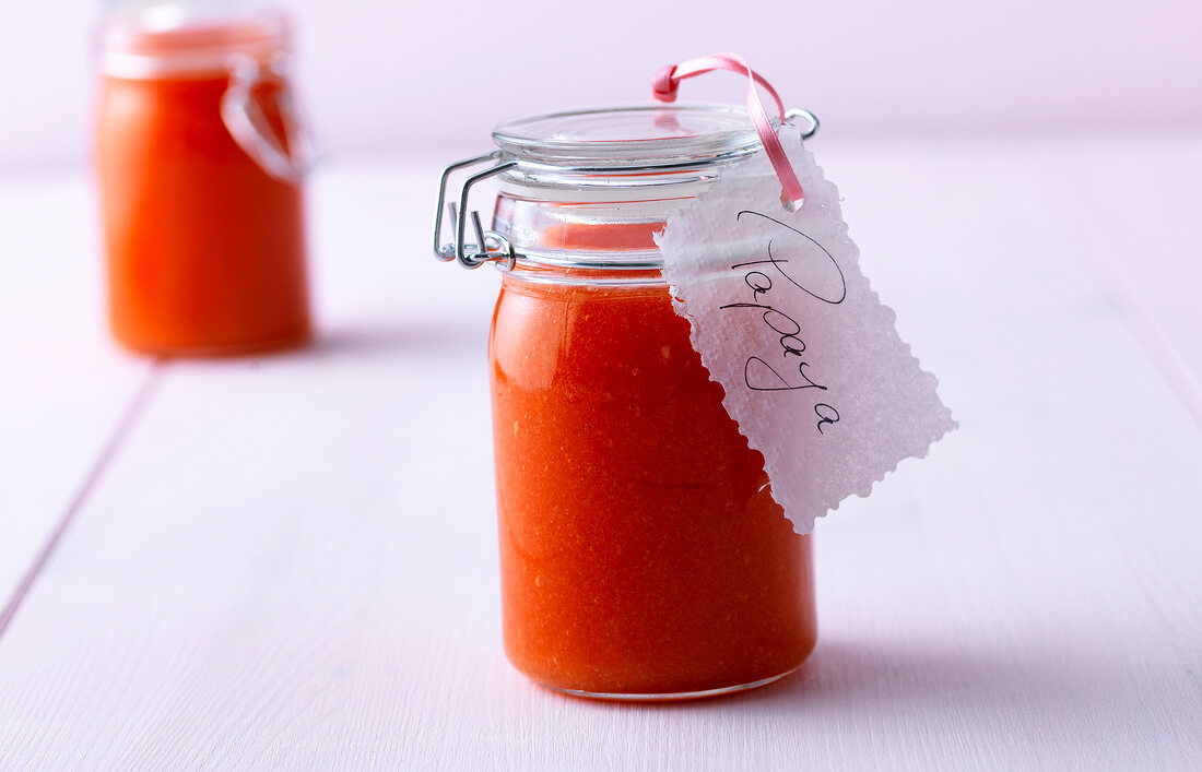 Close-up of cold stirred papaya jam in glass jar on white background
