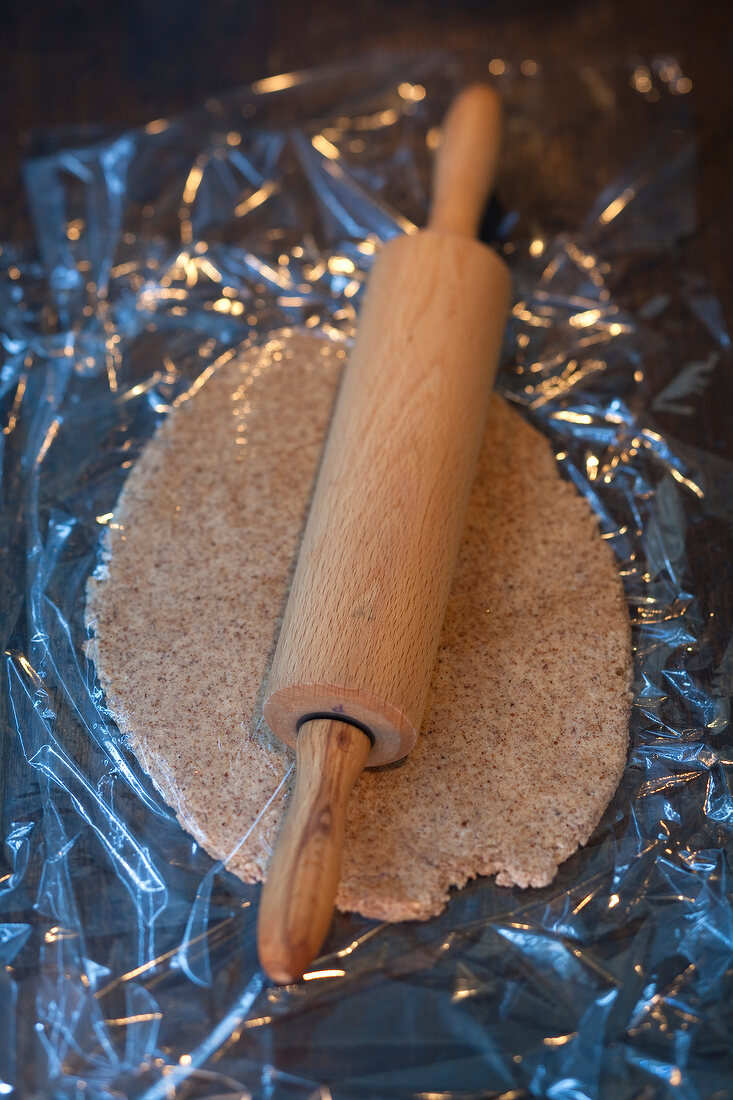 Dough with rolling pin on plastic for preparation of Christmas cookies, step 2