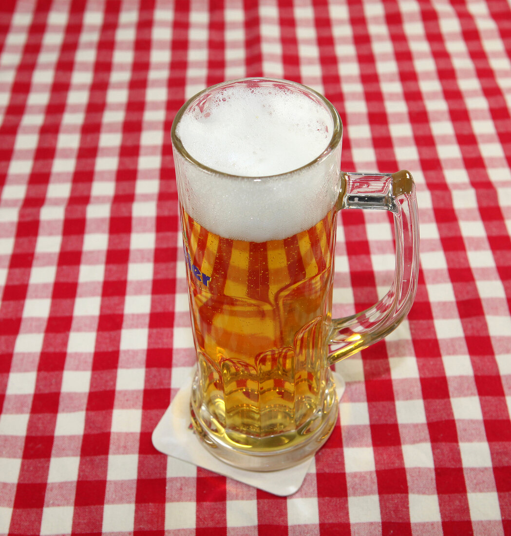 Beer in beer mug on red and white checked napkin