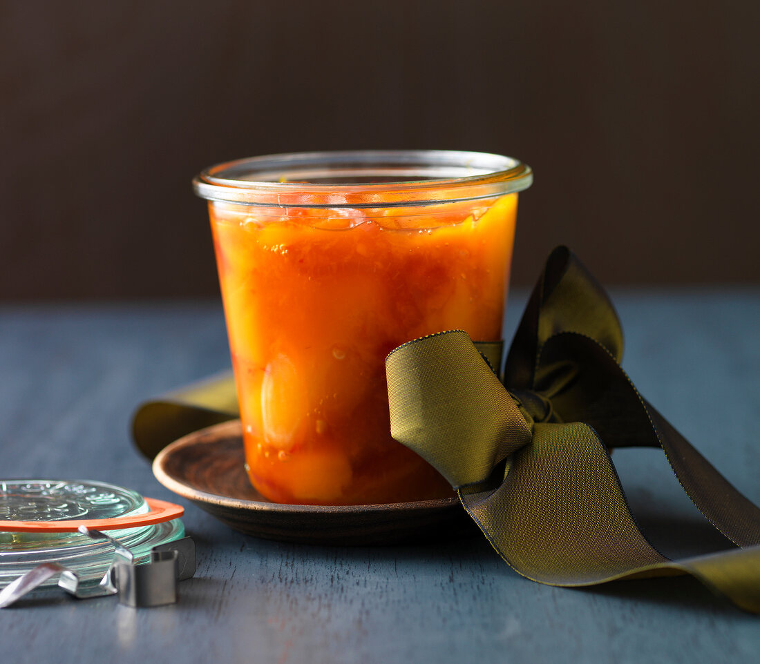 Close-up of mango chutney in glass with green ribbon