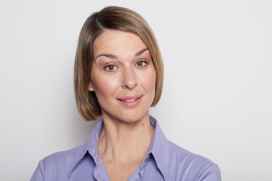 Portrait of pretty woman wearing purple shirt with raised eyebrows, smiling