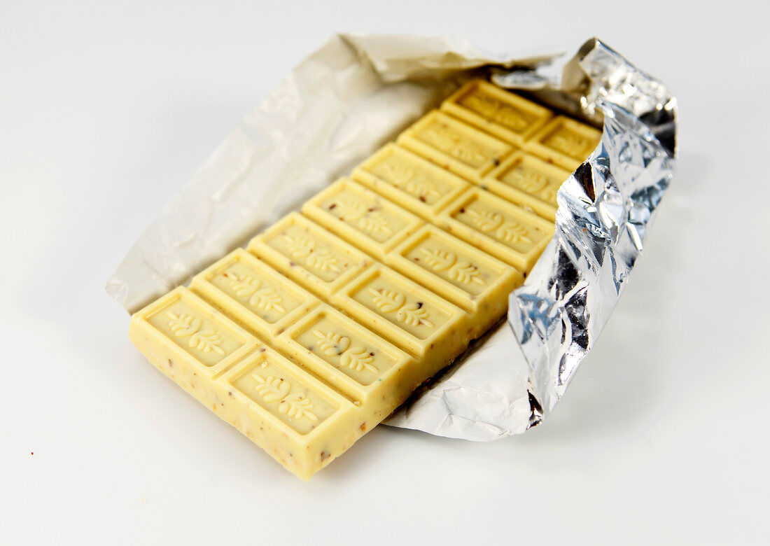 Crispy white chocolate bar on silver foil on white background