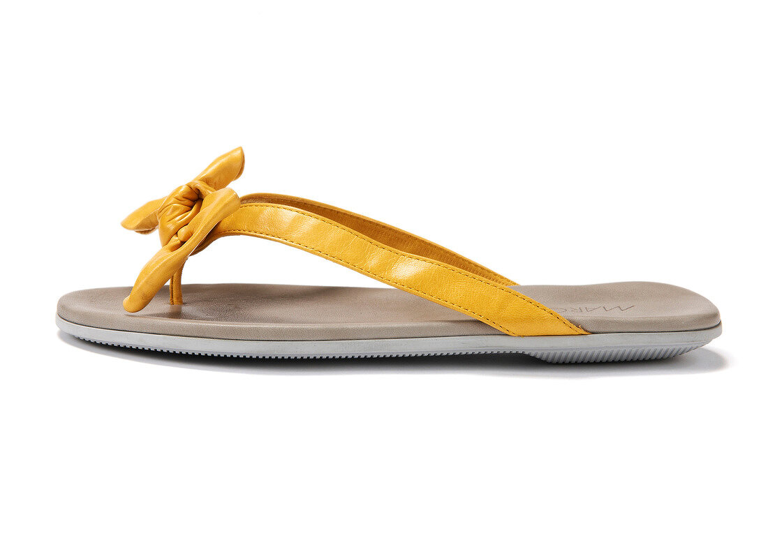 Close-up of yellow sandal made of nappa leather with decorative bow