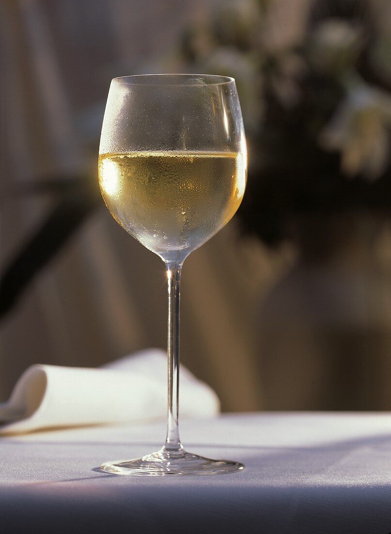 Ein Glas Weißwein auf weißem Tischtuch