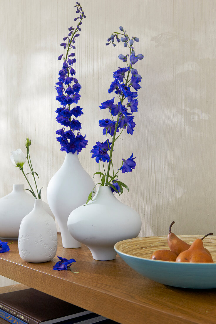 Variety of white vases with purple flowers on wooden surface