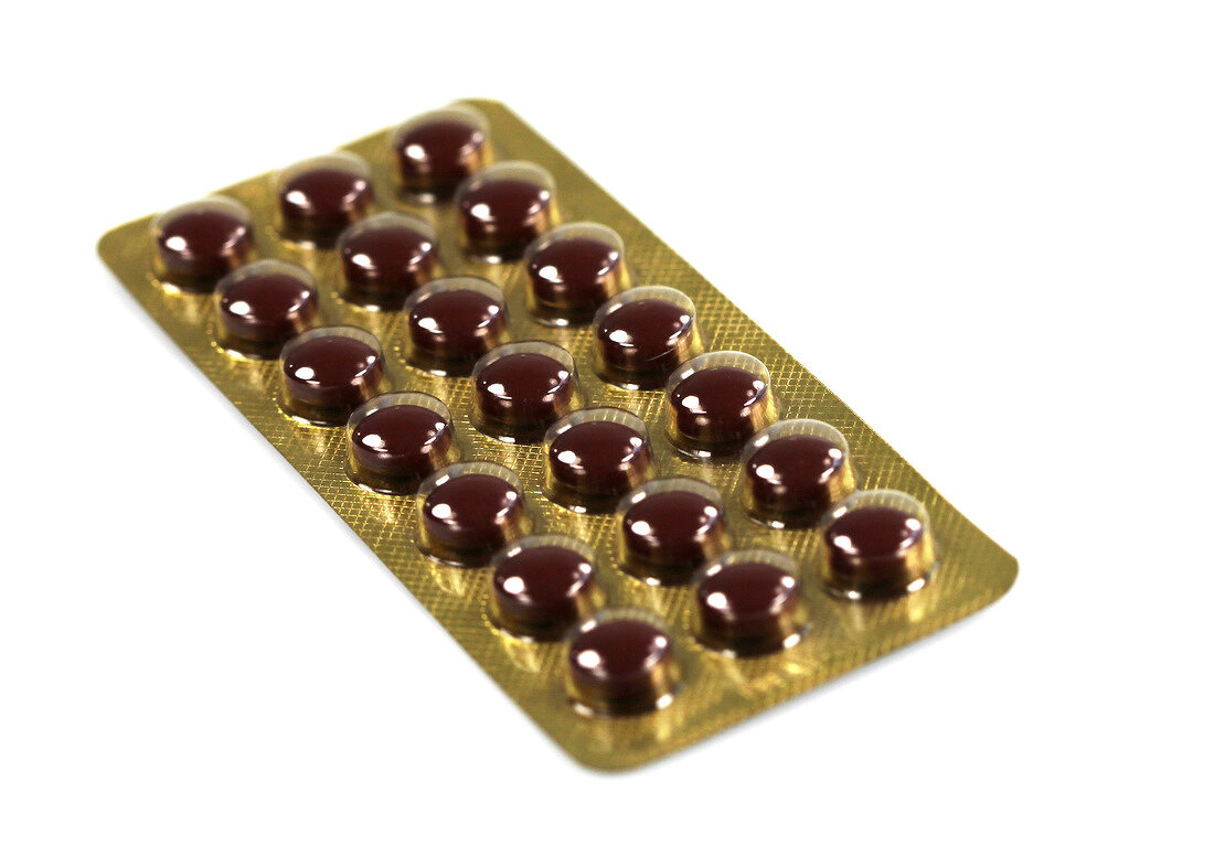 Close-up of red tablets in pack on white background, cut out