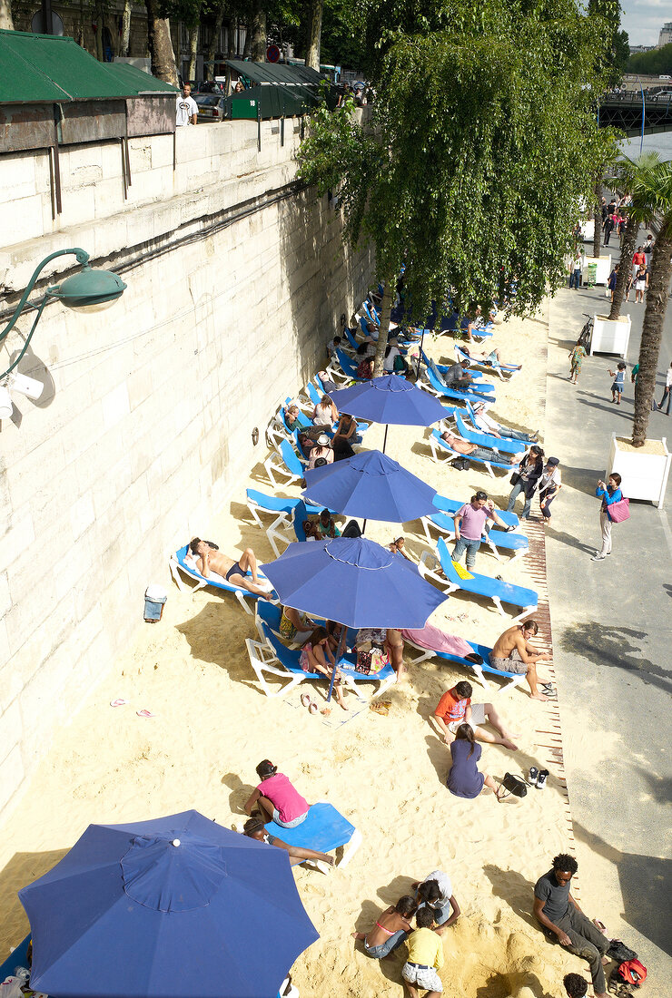 People relaxing on beach beside Seine river in Paris, France