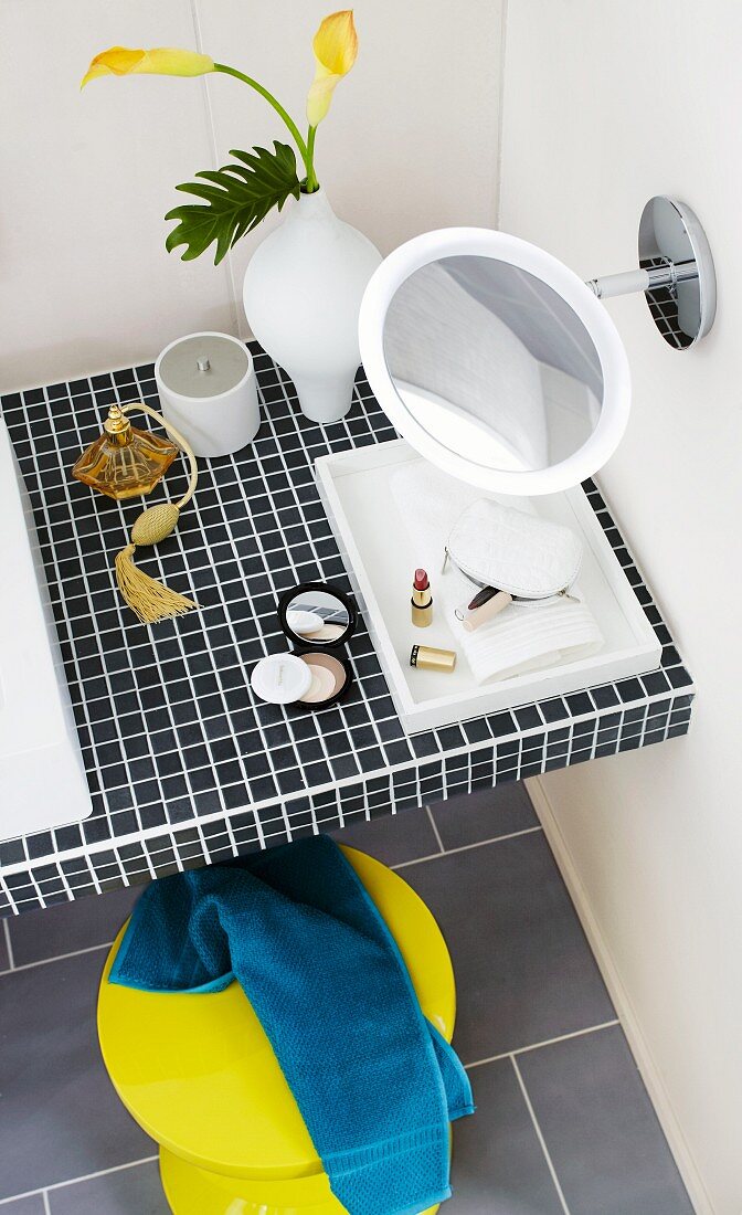 View down onto makeup mirror on washstand with mosaic tiles