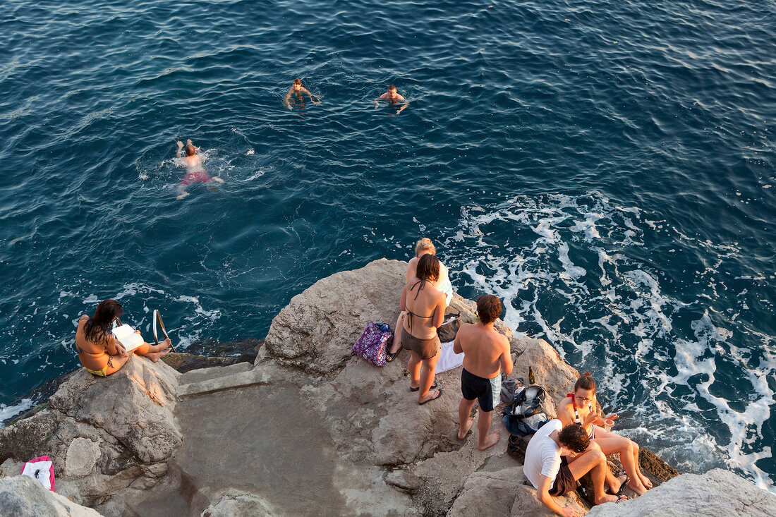 People enjoying bath and standing on rocks, Croatia