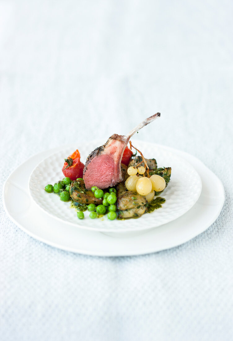 Rack of lamb with vegetables and olive pesto on plate