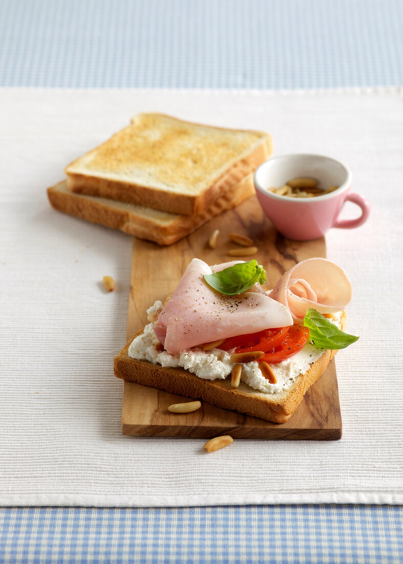 Toast with tomato and ham on wooden board