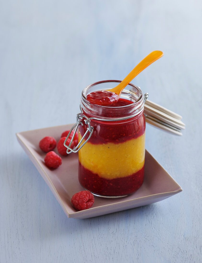 Mango raspberry jam in glass jar on plate