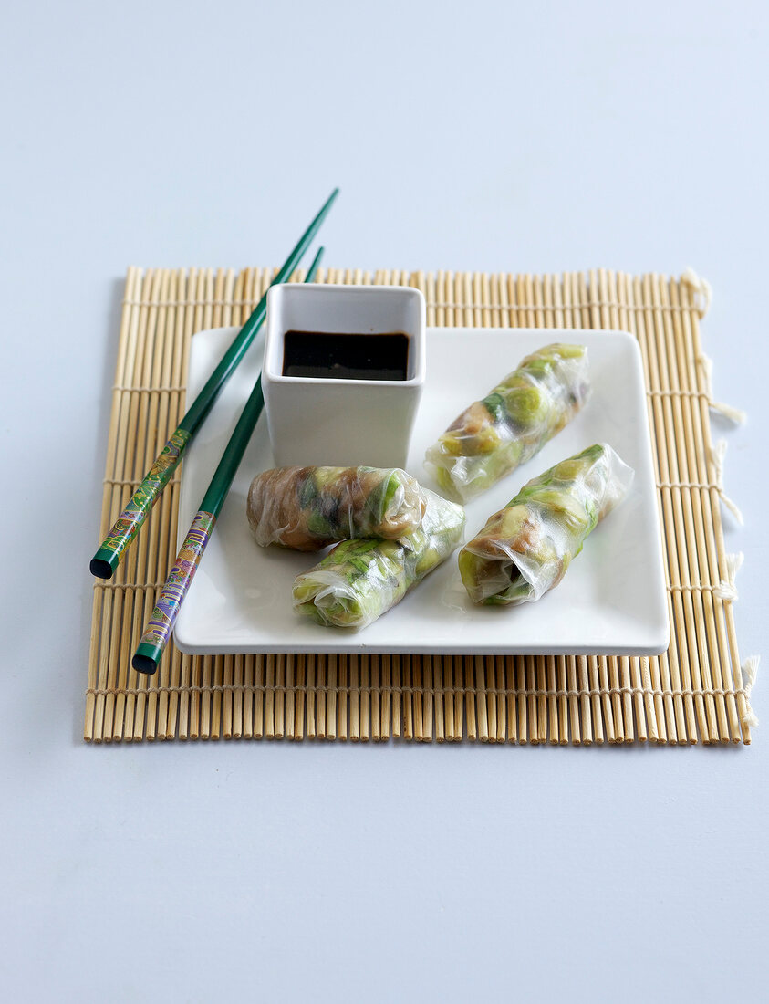 Mackerel rolls with dip and chopsticks on plate