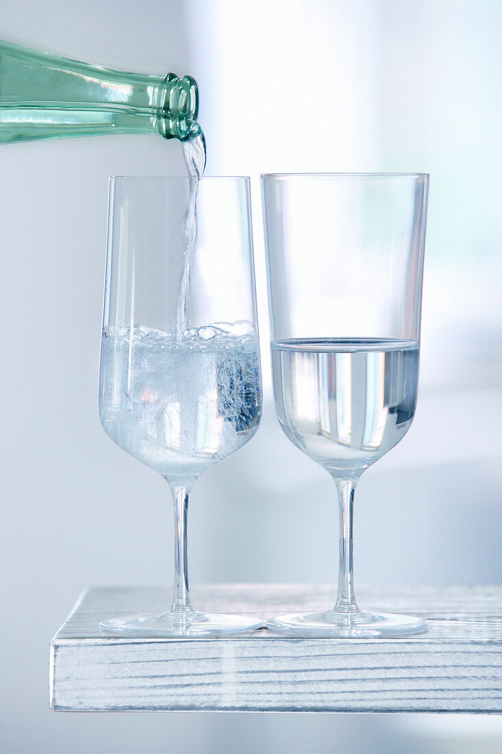 Two glasses being filled with water