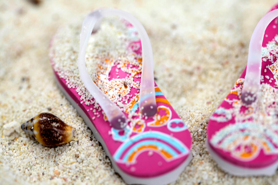 Close- up of flip flops and shells on sand
