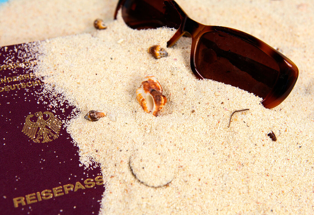 Close-up of sunglasses and passport on sand