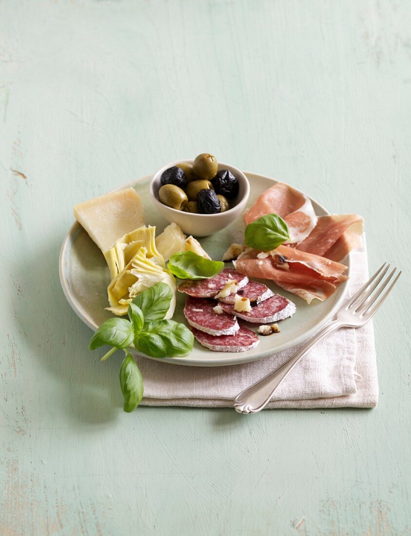 An appetiser platter of salami, ham, cheese, olives and artichokes