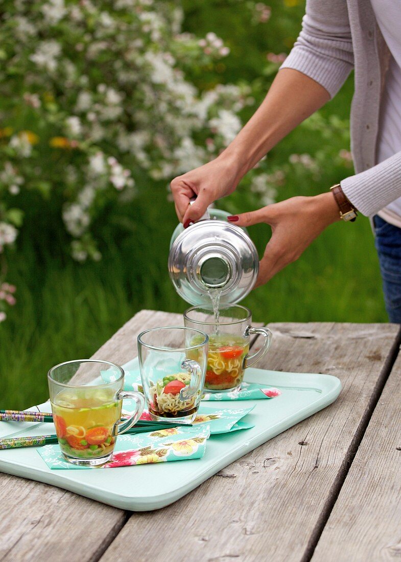 Frau giesst Suppe mit Wasser auf