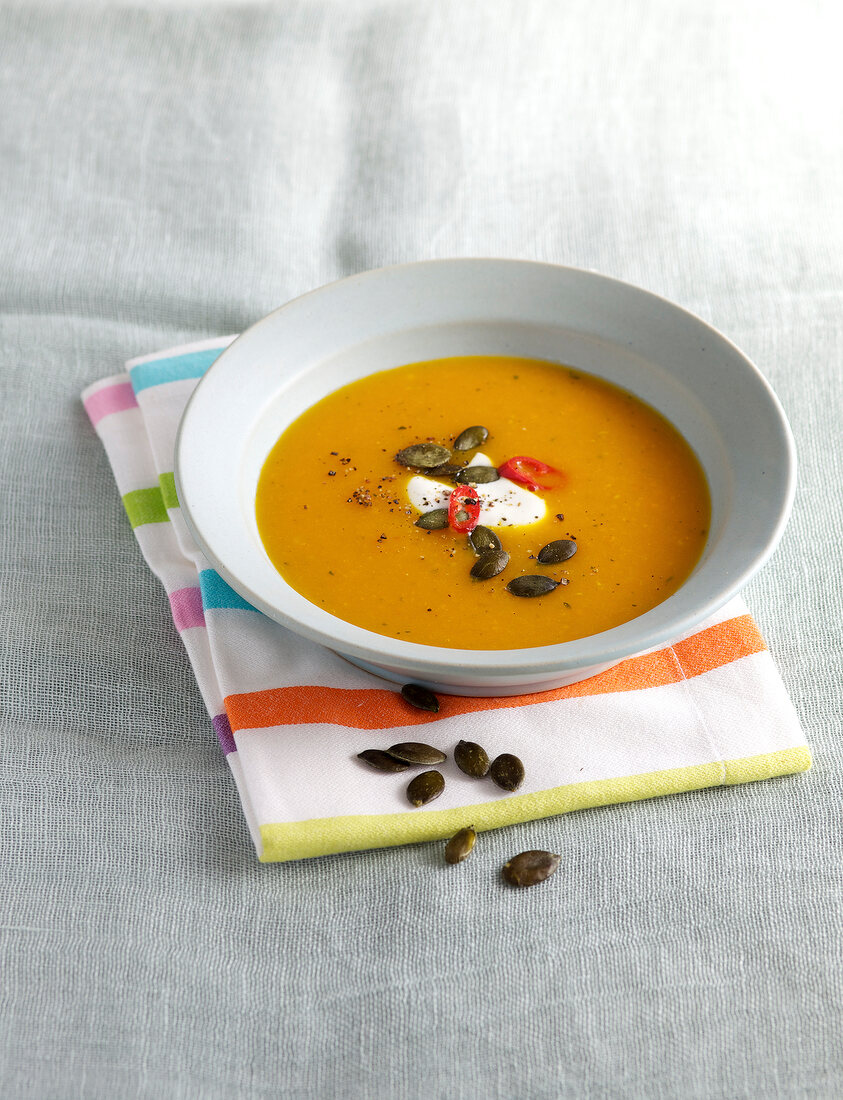 Pumpkin and yoghurt soup in bowl on napkin
