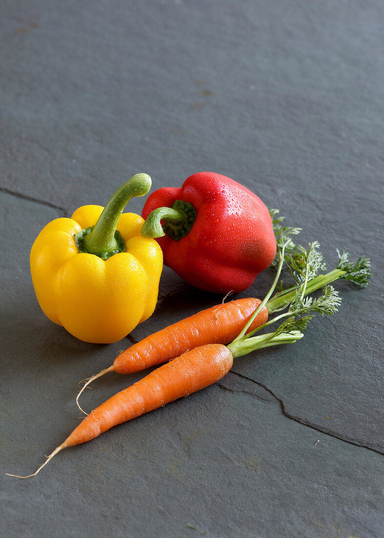 Fresh pepper and carrots on gray surface